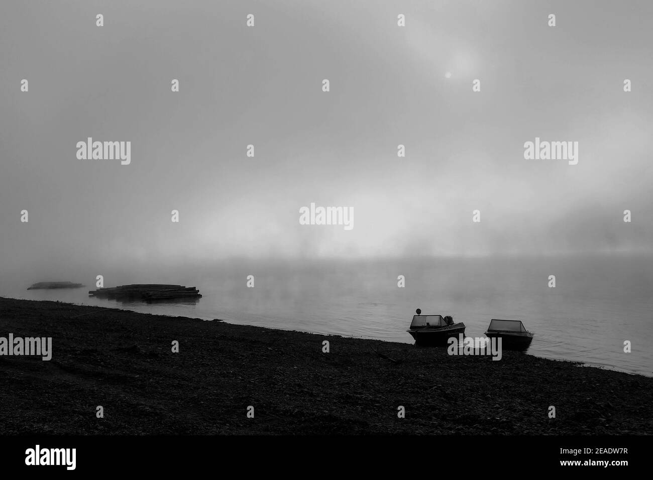 Morning fog on the Lena River, taiga of Siberia. Fishing boats on the riverbank in the misty dawn Stock Photo