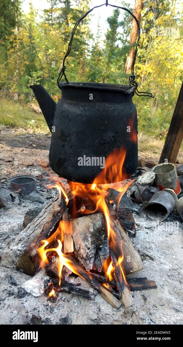 https://c8.alamy.com/comp/2EADWN5/over-the-fire-hangs-an-old-camp-kettle-black-with-soot-and-burning-teapot-on-the-fire-2EADWN5.jpg