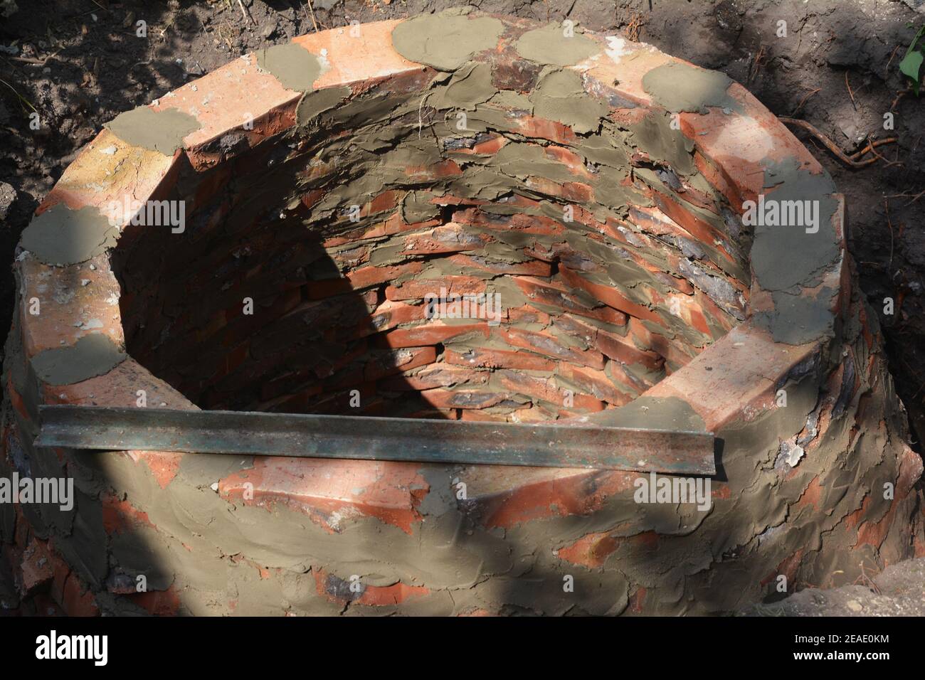 Building a round septic tank, sewer, sewage, cesspool or soak pit for domestic wastewater from red bricks for a private home. Stock Photo