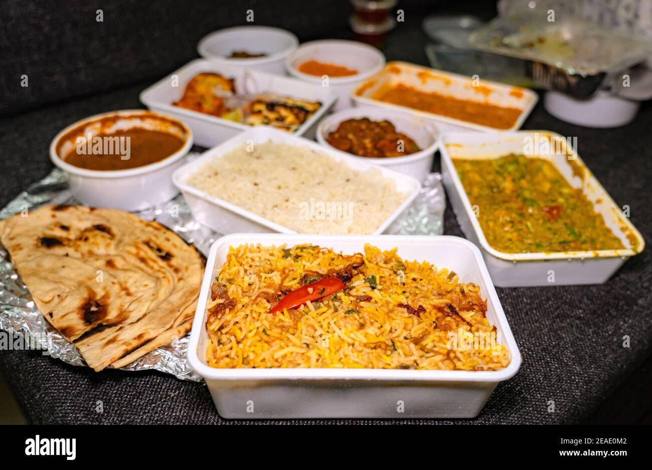 Selective focus of Vegetable Biryani in a white takeout box. Many foods in takeout boxes blurred in the background. Stock Photo