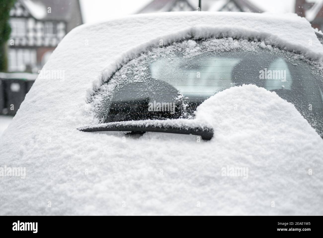 Rear windscreen wiper cleaning snow from back window of small car windscreen on fresh icy day early morning powder deep snowfall Stock Photo