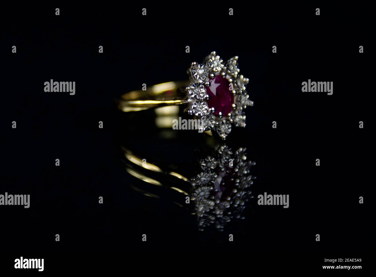 Red ruby and diamond 18 carat gold ring set on a reflected surface with black background Stock Photo