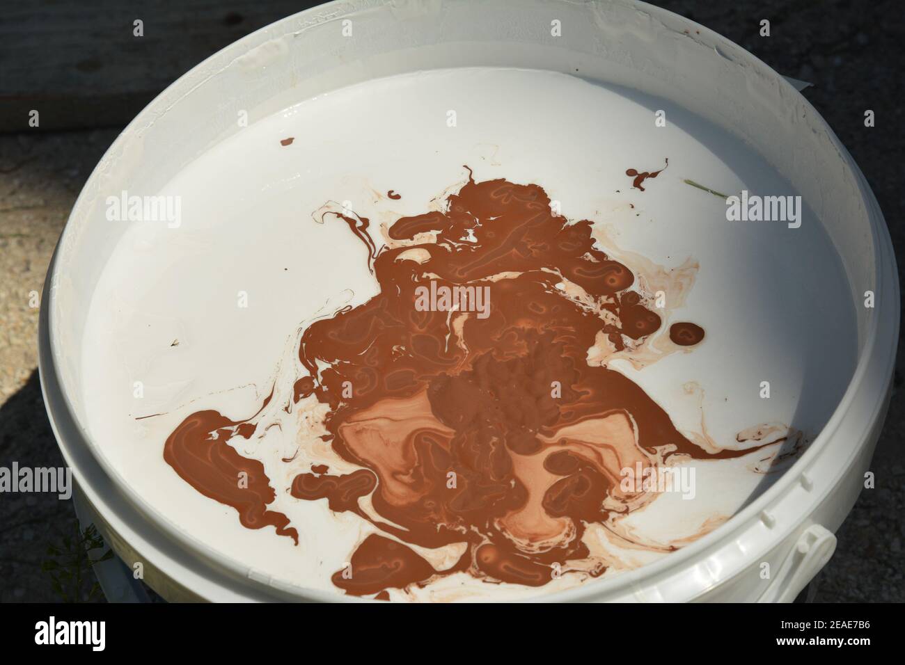 Mixing white and brown paint in a bucket for exterior wall painting to
