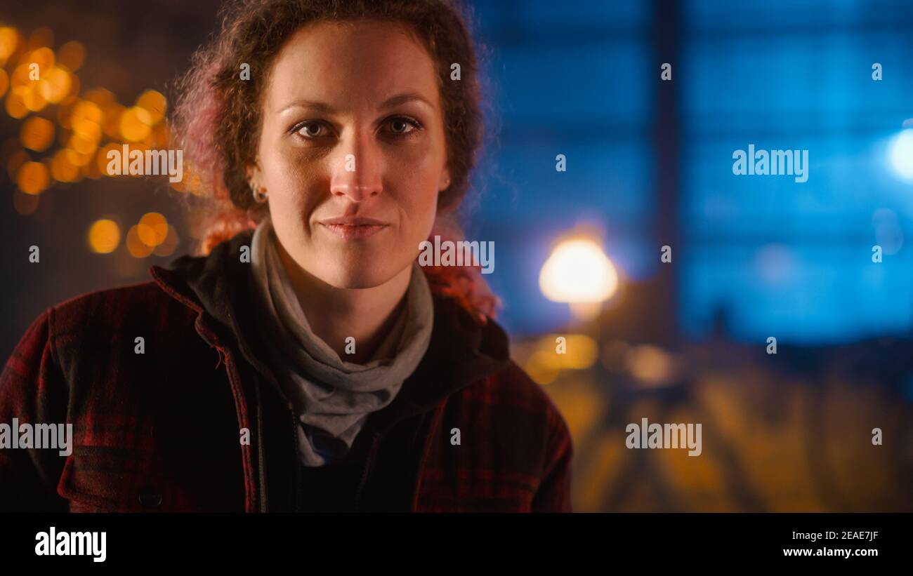 Young Beautiful Empowering Woman Gently Smiles at the Camera. Authentic Fabricator Wearing Work Clothes in a Metal Workshop. Sparks Flying on the Stock Photo