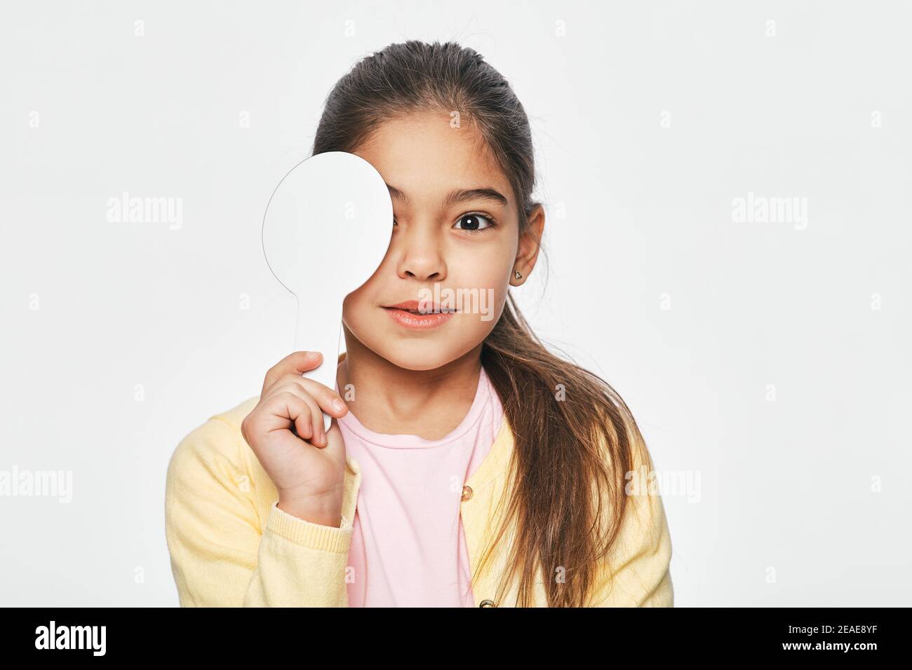 Mixed race little girl having eye exam with one eye covering using a