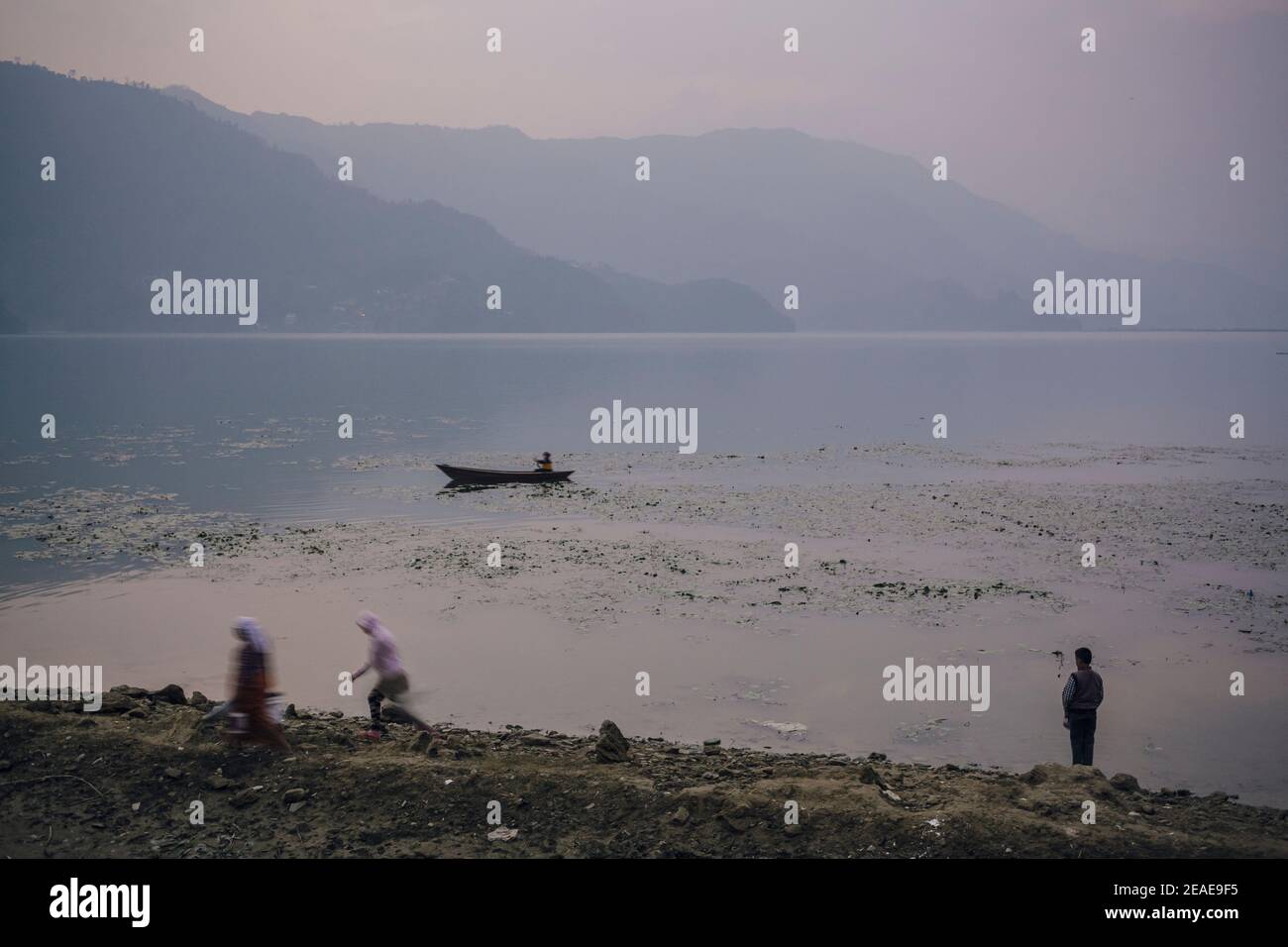 A wooden boat approaches the shore of Phewa Lake. Pokhara. Nepal. Stock Photo