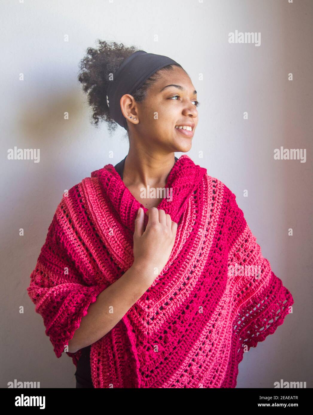 Elegant red and pink poncho or shawl tied by a young smiling and happy
