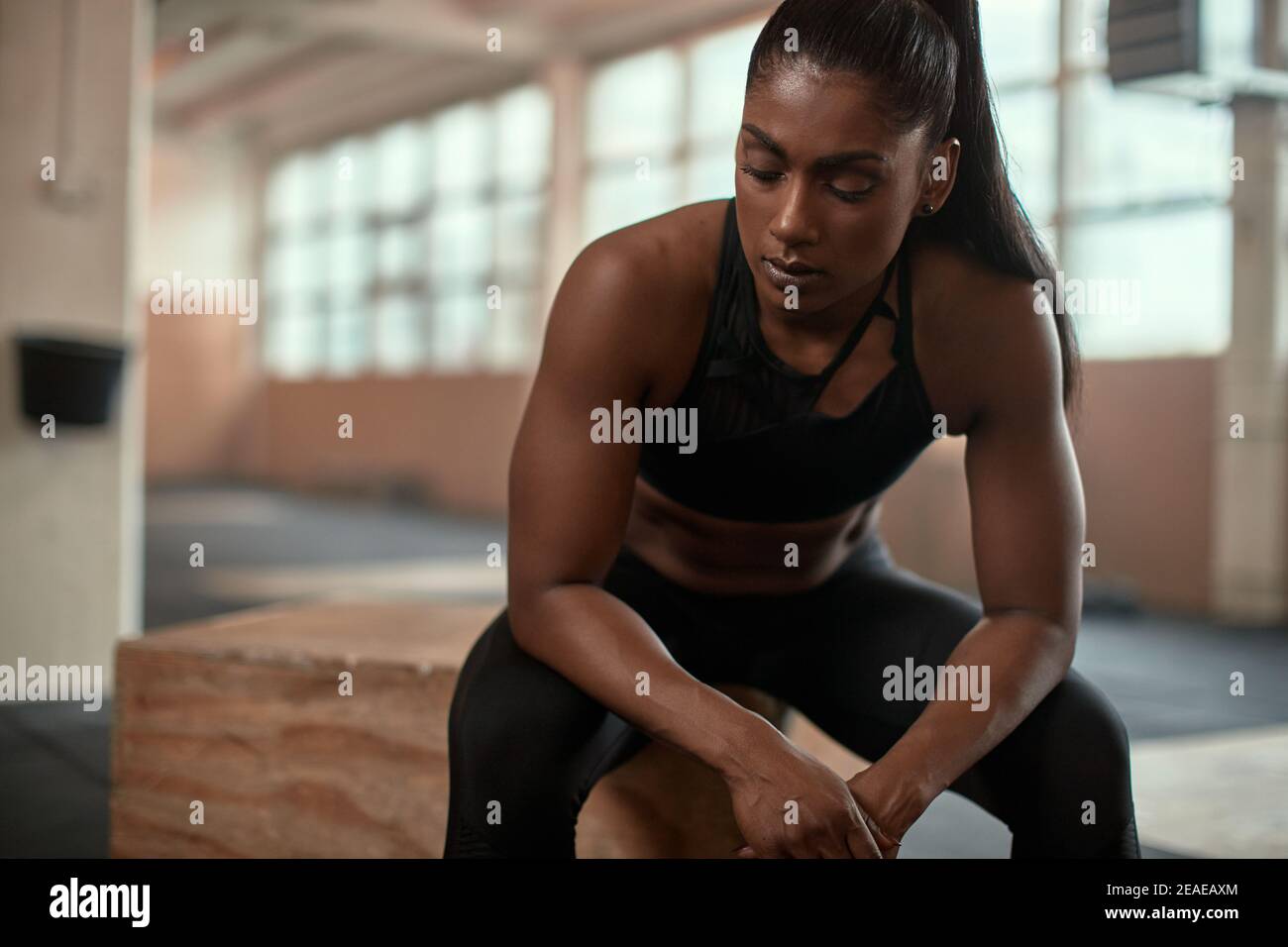 Muscular young Indian woman in sportswear looking tired after a workout session at the gym Stock Photo