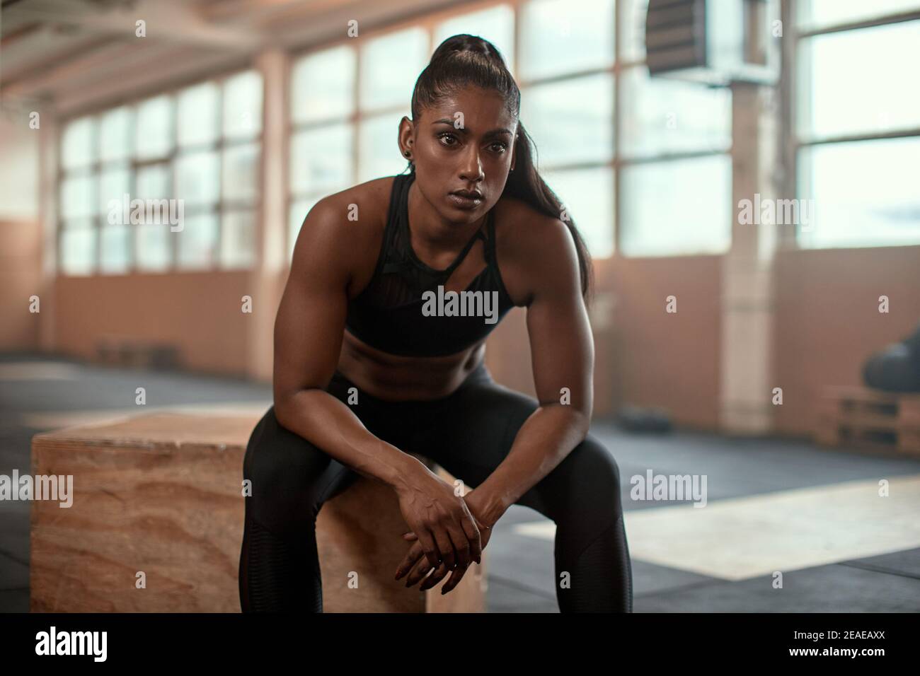 Fit young Indian woman in sportswear taking a break after a box jump  workout session in a gym Stock Photo - Alamy