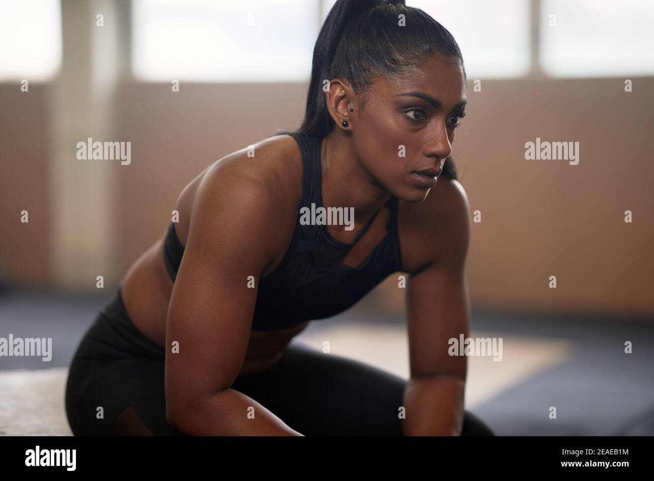 Muscular young Indian woman in sportswear taking a break after workout session in a gym Stock Photo