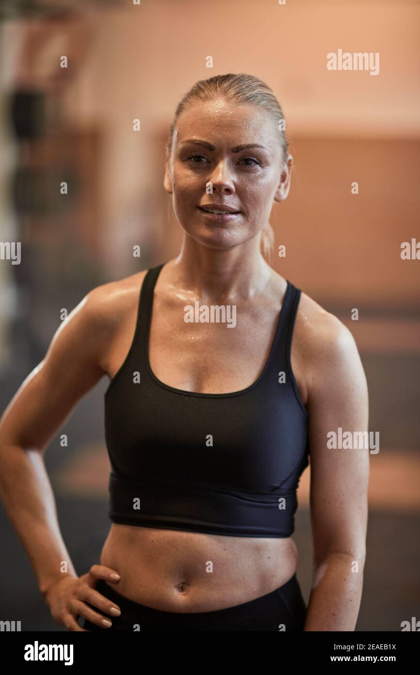 Fit young woman in sportswear sweating while standing in a gym after a workout session Stock Photo