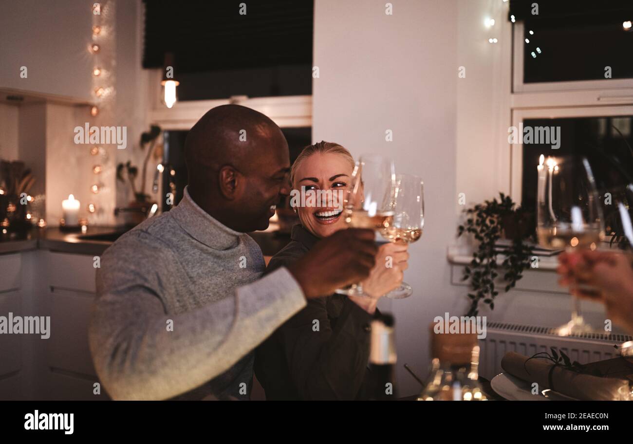 Laughing young couple toasting friends with glasses of wine during a candlelit dinner party Stock Photo