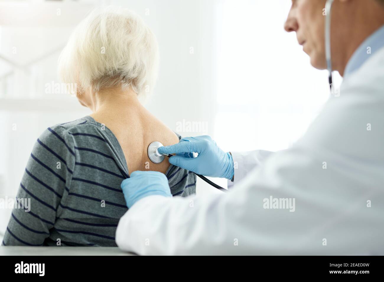 Doctor examining female patient with stethoscope in clinic Stock Photo ...