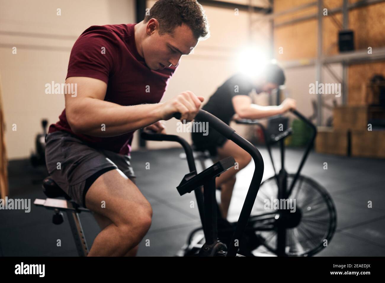 Two fit young man in sportswear exercising on stationary bikes during an exercise class at the gym Stock Photo