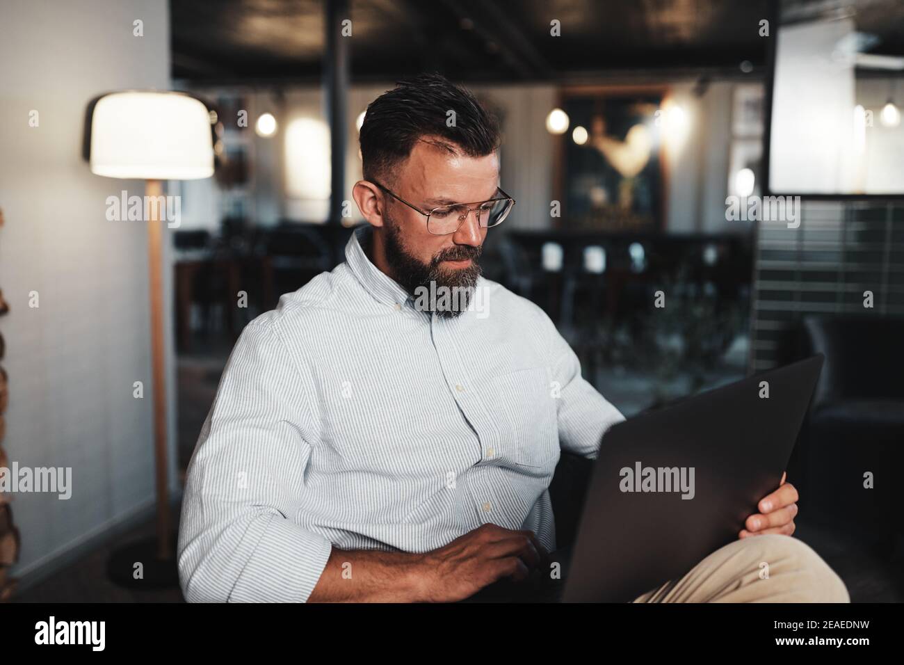 Young businessman working online with a laptop while sitting in the lounge area of a modern office Stock Photo