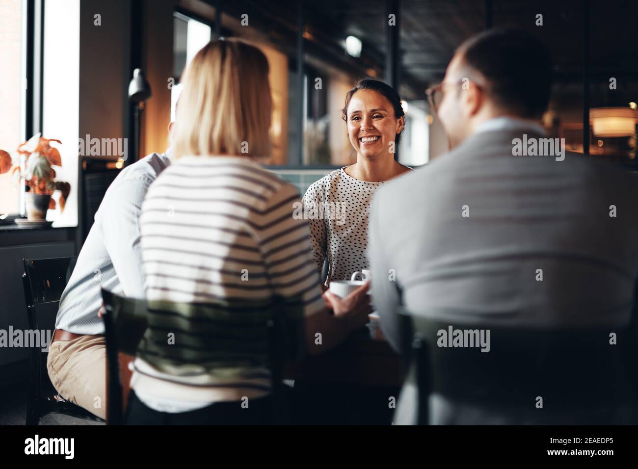 Laughing young businesswoman having coffee with a group of colleagues during their office break Stock Photo