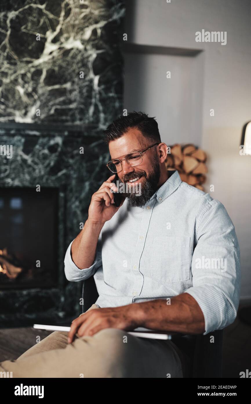 Smiling young businessman talking with a client on his cellphone while sitting in the lounge area of a modern office Stock Photo