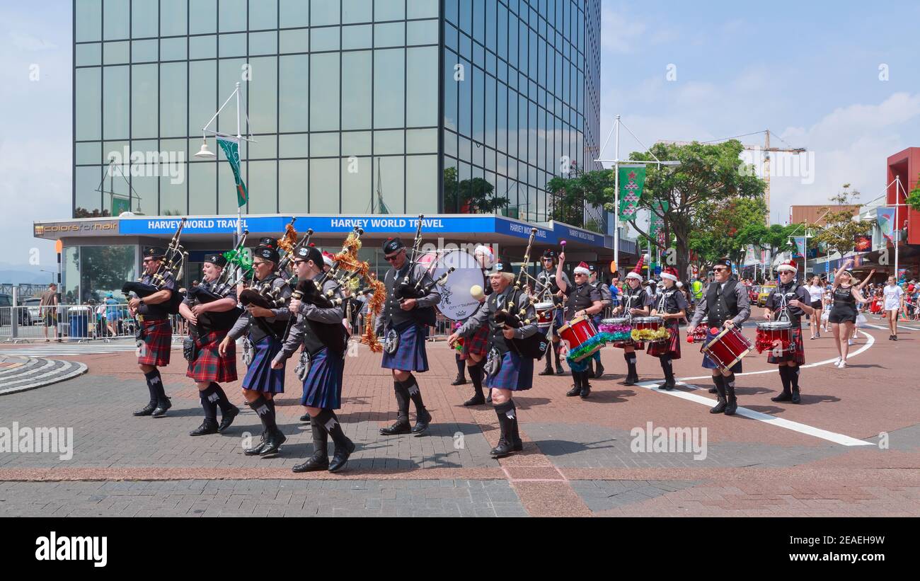 A Scottish bagpipe and drum band marching in a Christmas parade, with tinsel decorations on their instruments. Tauranga, New Zealand Stock Photo