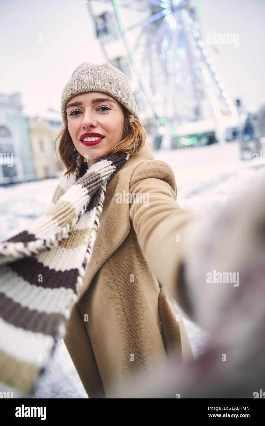 Merry pretty woman taking selfie on snowy day outdoors Stock Photo