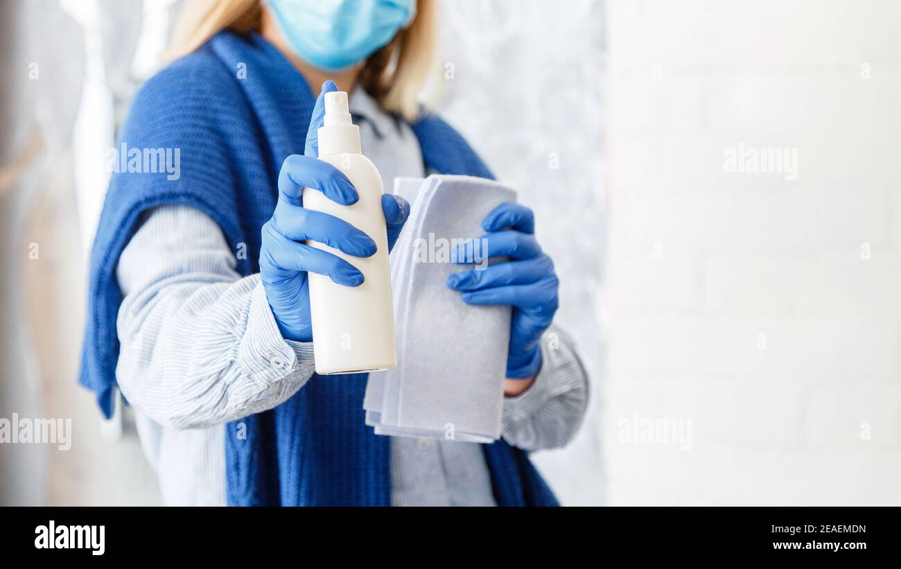 Cleaning antibacterial alcohol spray. Woman in rubber blue gloves clean