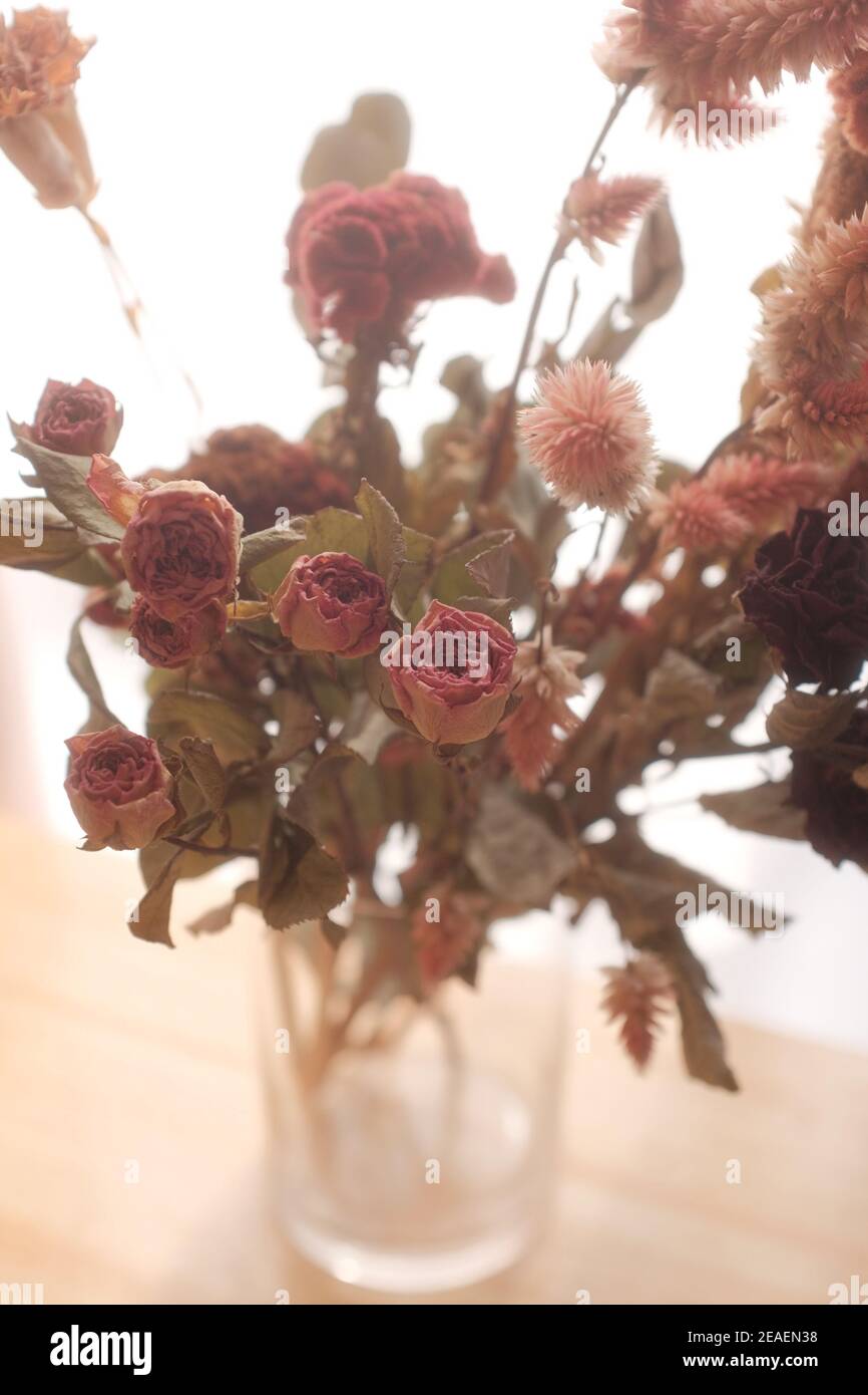 Vertical shot of beautiful dried roses, celosias, and astilbe branches in a vase on the table Stock Photo