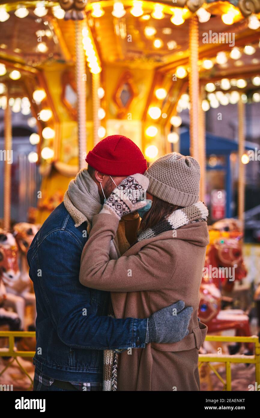 Romantic couple in medical masks hugging in amusement park Stock Photo ...