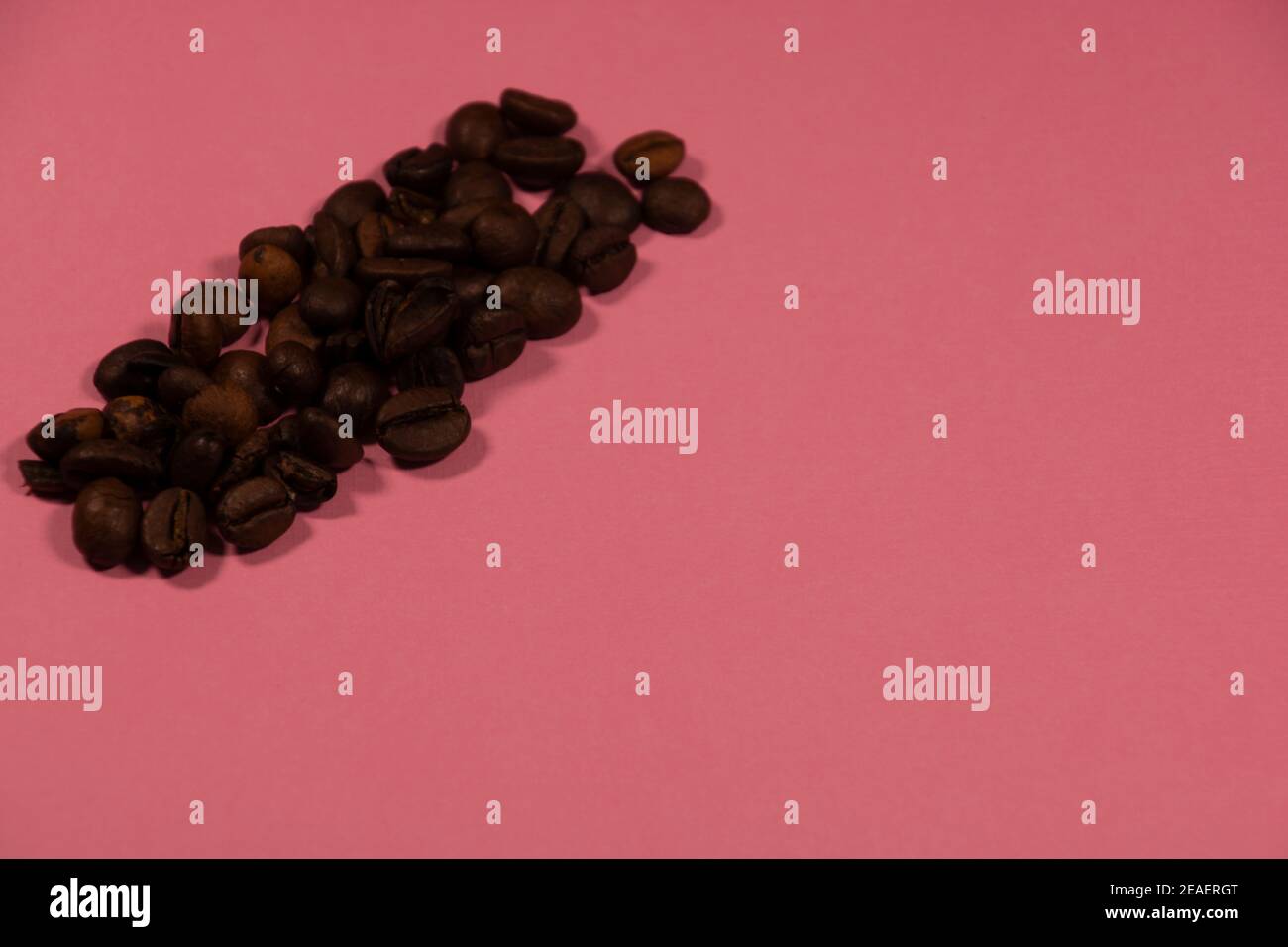 roasted coffee beans on pink colored background with copy space Stock Photo