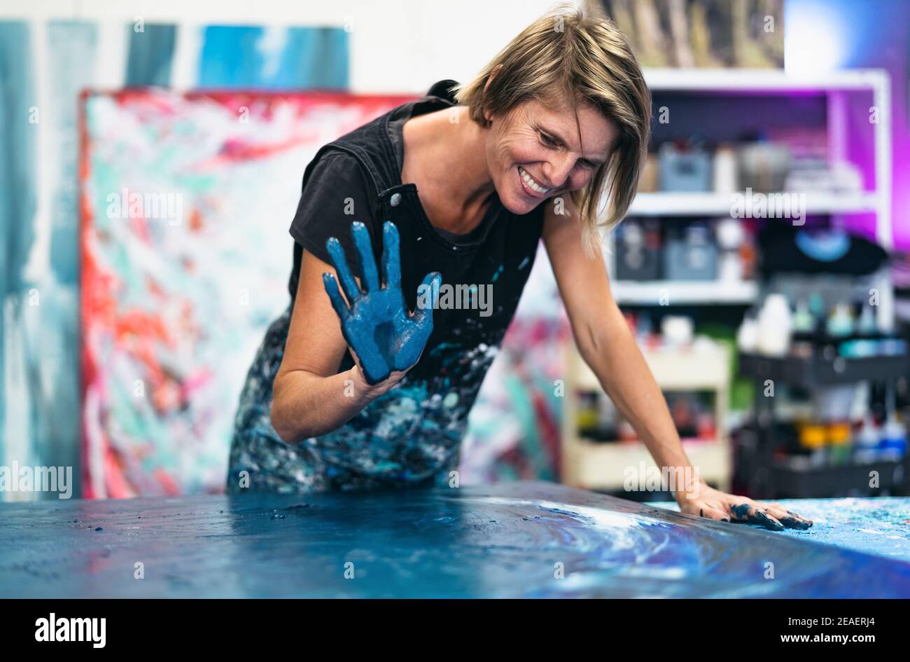 Woman artist painting with hands on canvas in workshop studio - Painter work and creative craft concept Stock Photo