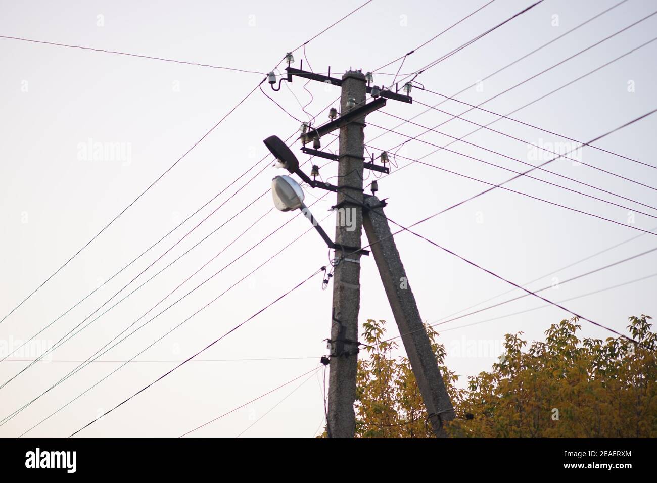 old stone pillar with lamp and wires on the white sky background Stock