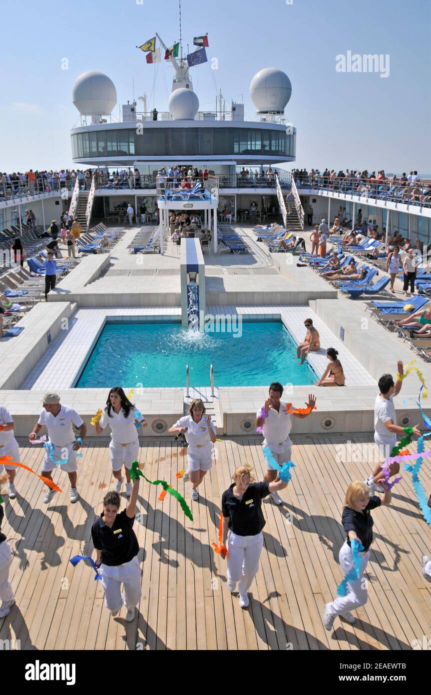 View of swimming pool sun deck on cruise ship liner Costa Classica ships entertainment staff promoting exercise by keeping active departing Dubai UAE Stock Photo