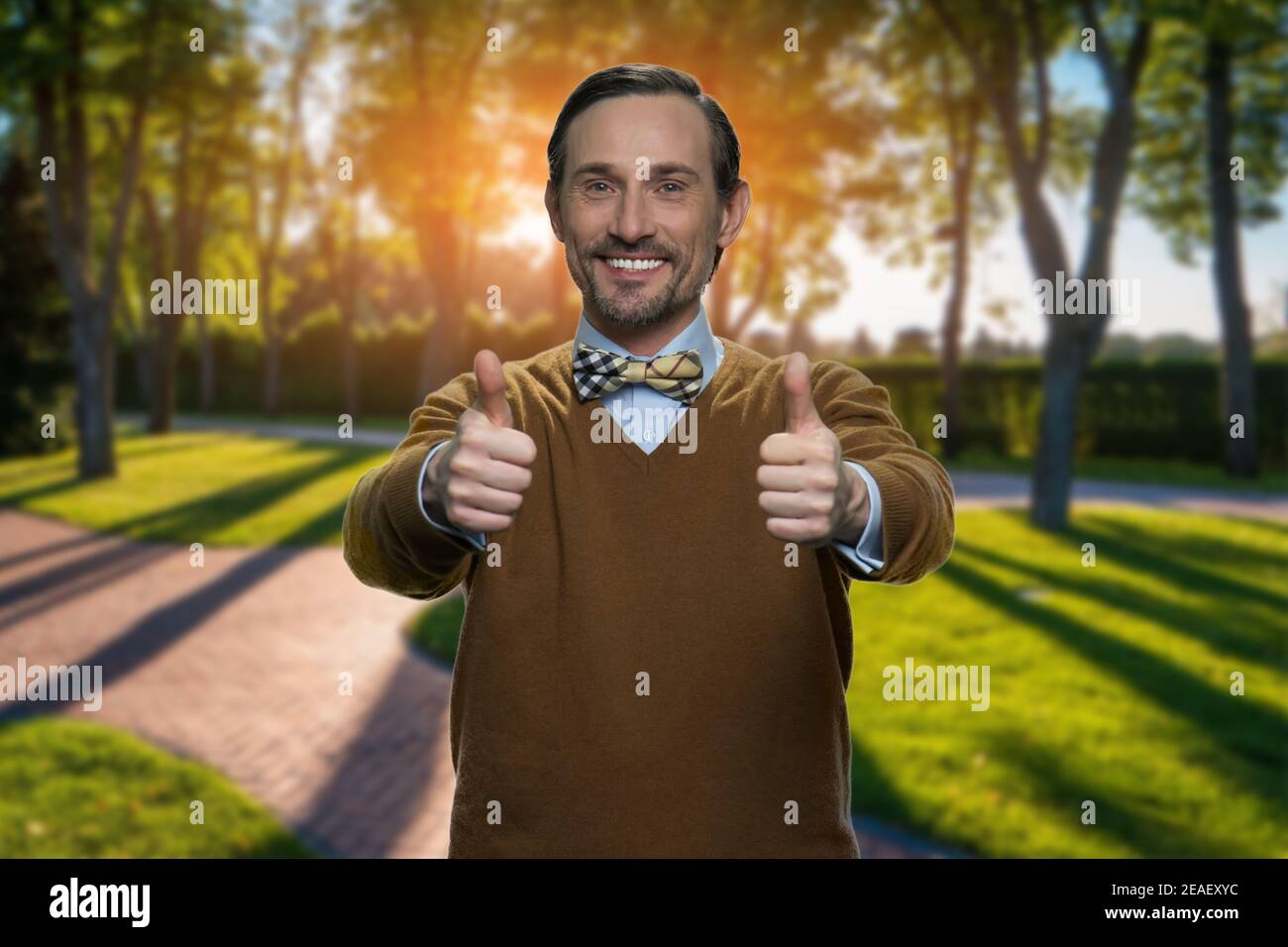 Mature man showing two thumbs up in the morning park. Stock Photo