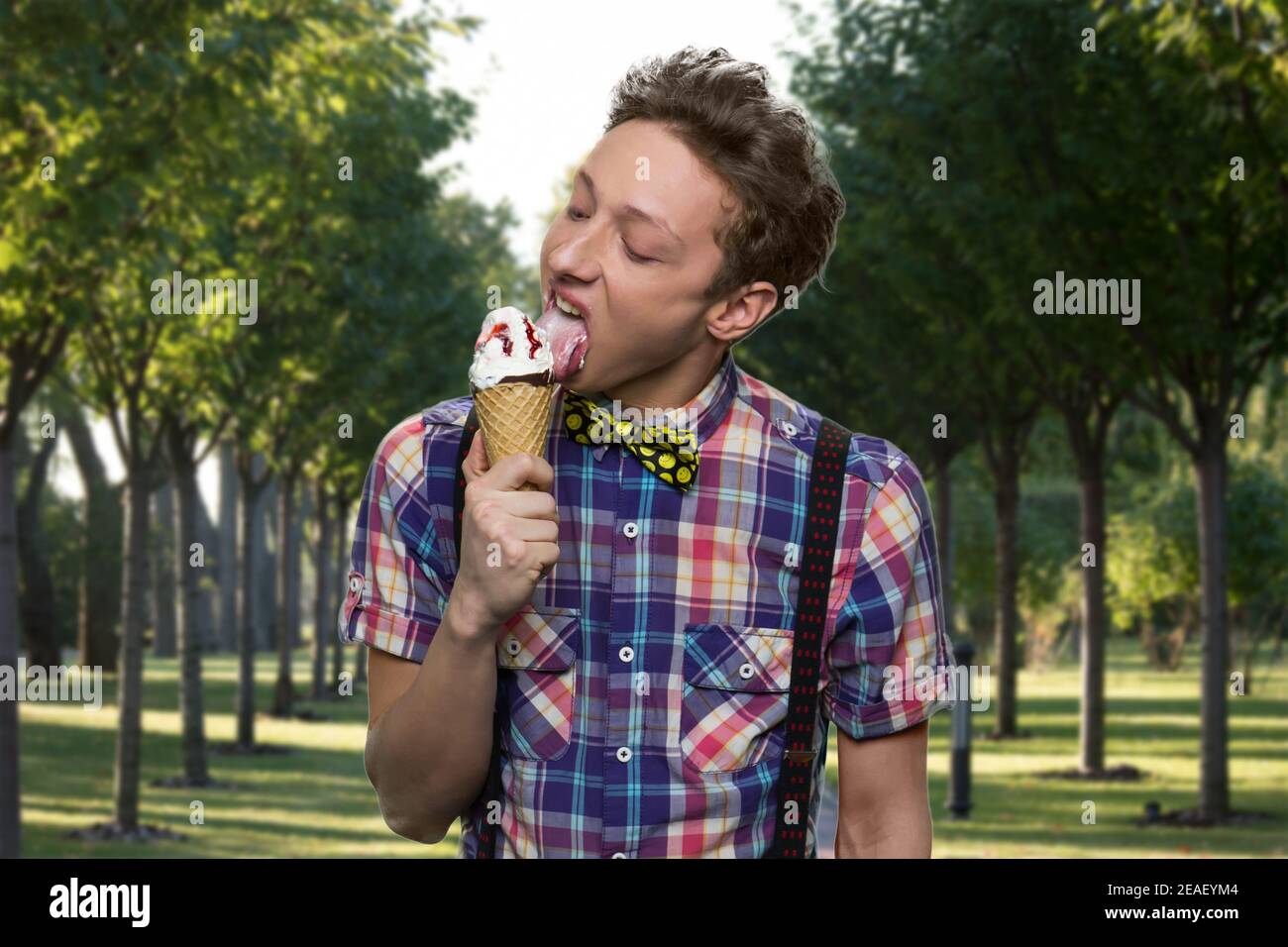 American teen boy in suspenders is licking ice-cream. Stock Photo
