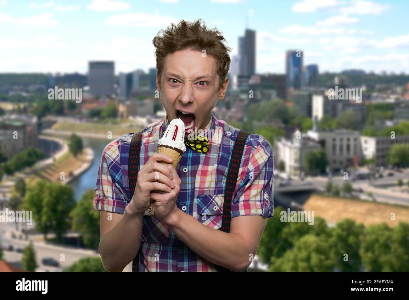 Boy with crazy eyes is biting an icecream. Stock Photo