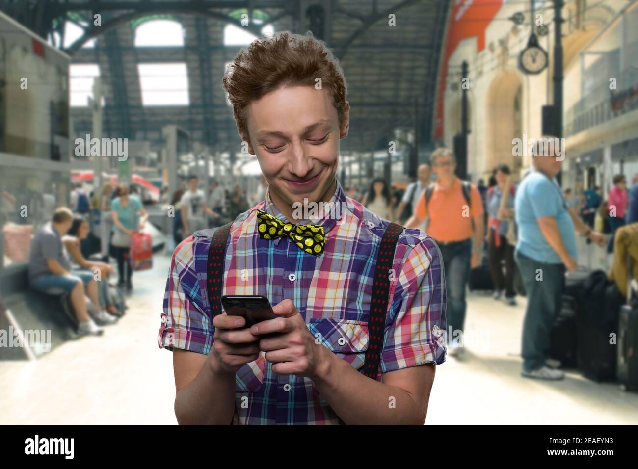 Smiling teenager is texting a message on his smartphone. Stock Photo