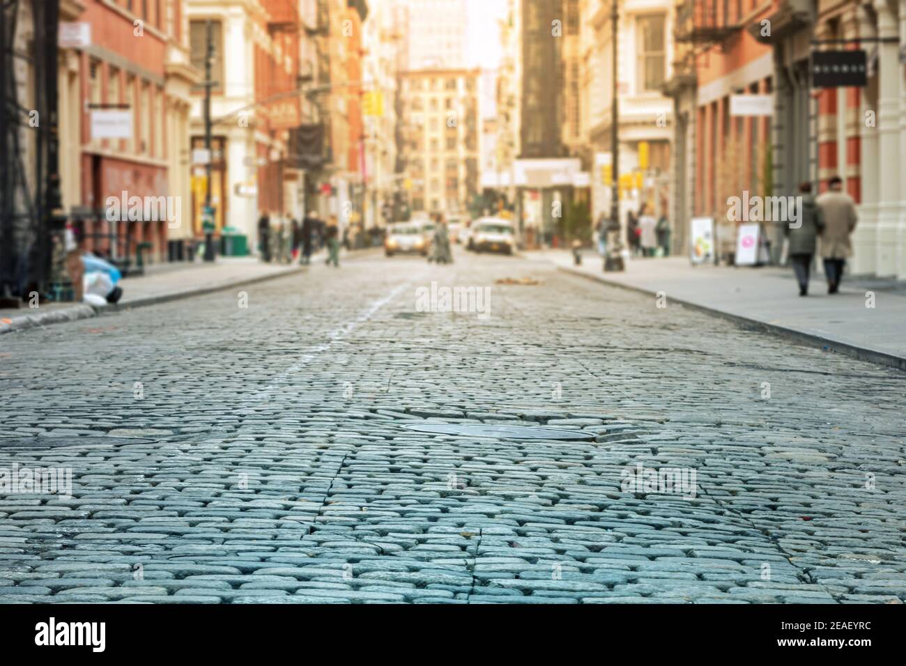 Cobblestone street with crowded intersection blurred in the sunlit