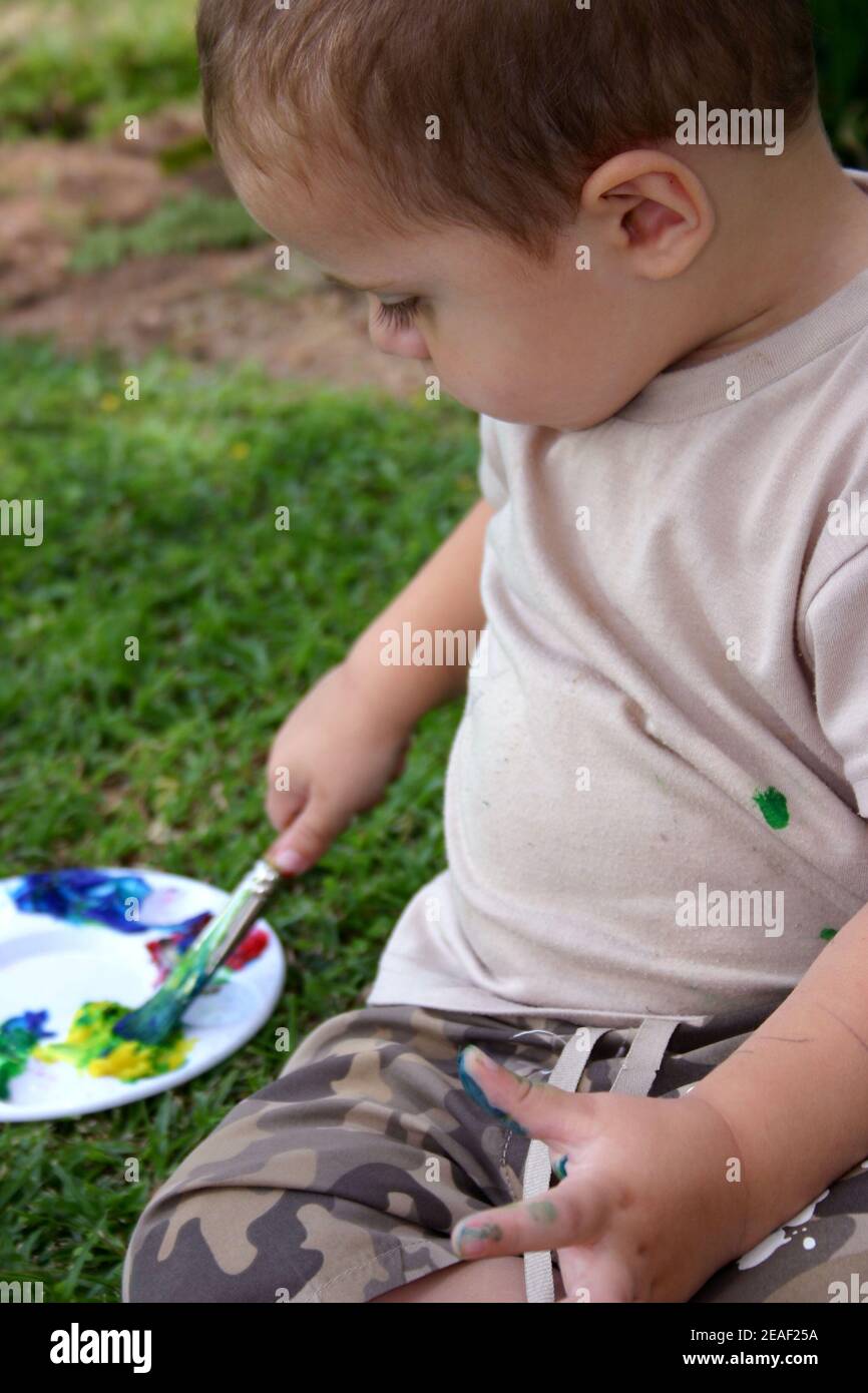 Toddler playing outdoors with paint Stock Photo