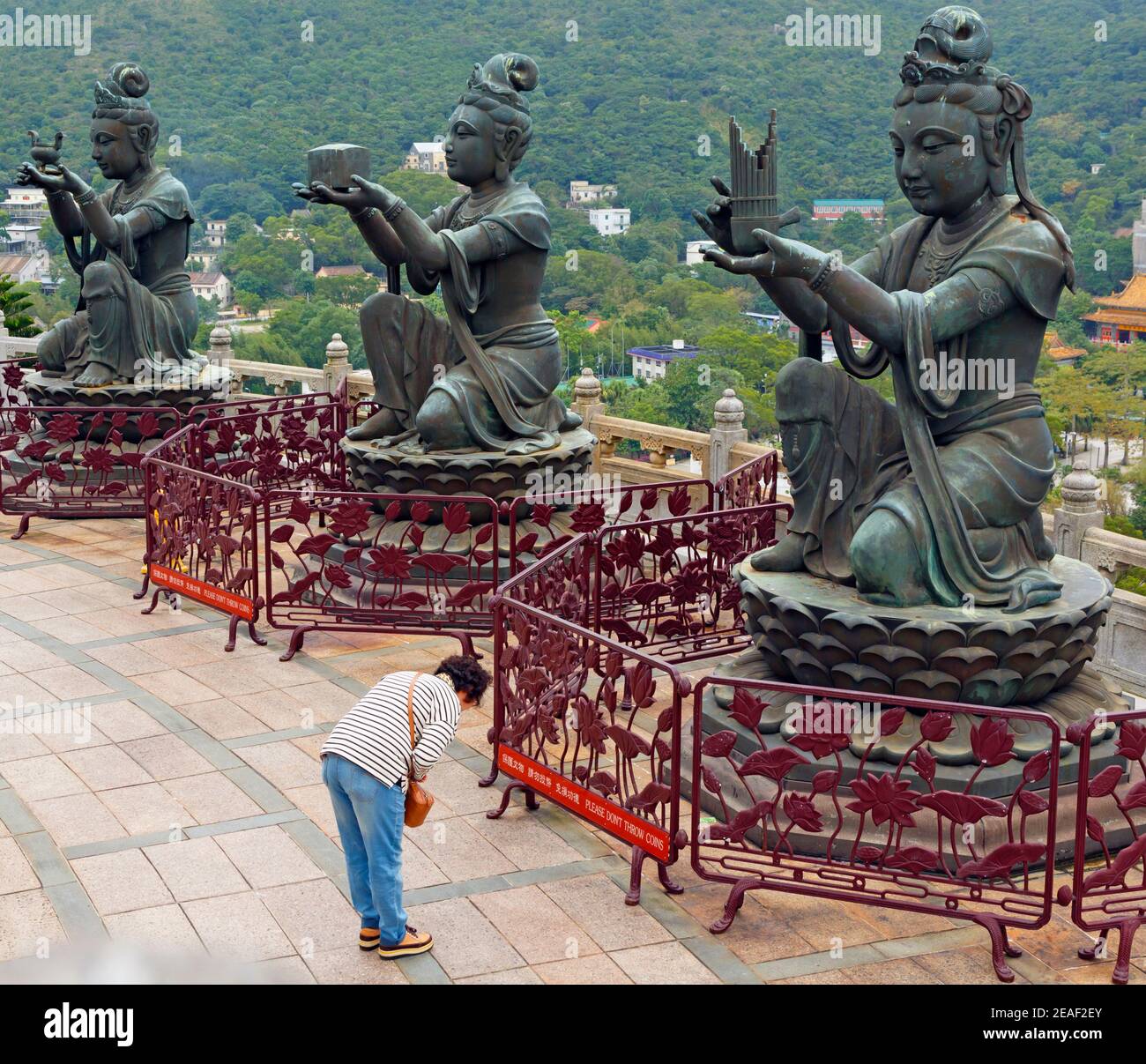 Hong Kong, China. The Buddhist Po Lin Monastery, Lantou Island.  Worshipper bowing to devas at the base of the Big Buddha statue.  In all there are si Stock Photo