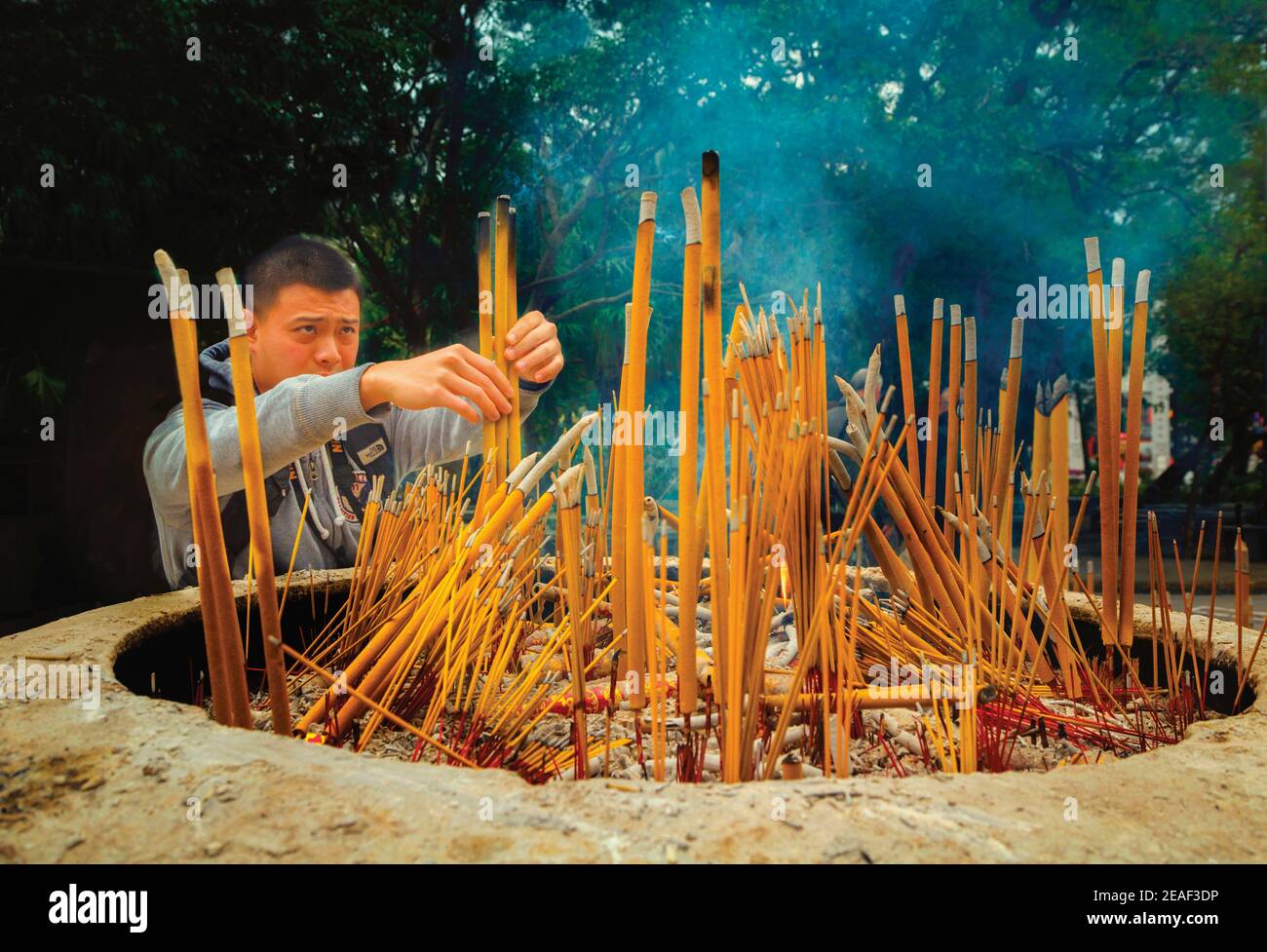 Hong Kong, China. The Buddhist Po Lin Monastery, Lantou Island.   A visitor burning incense sticks. Stock Photo