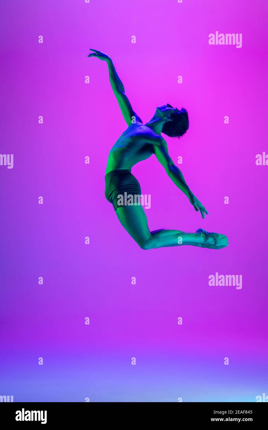 Weightless. Young and graceful ballet dancer on purple studio ...