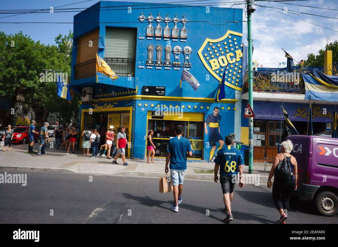 Buenos Aires, Argentina - January, 2020: Football fans of Boca Juniors club crossing road near La Bombonera stadium and fan shop in front of it Stock Photo