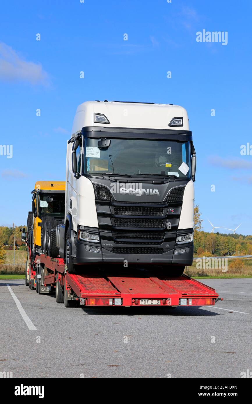 Vehicle carrier carrying two new Scania trucks, white R650 and yellow ...