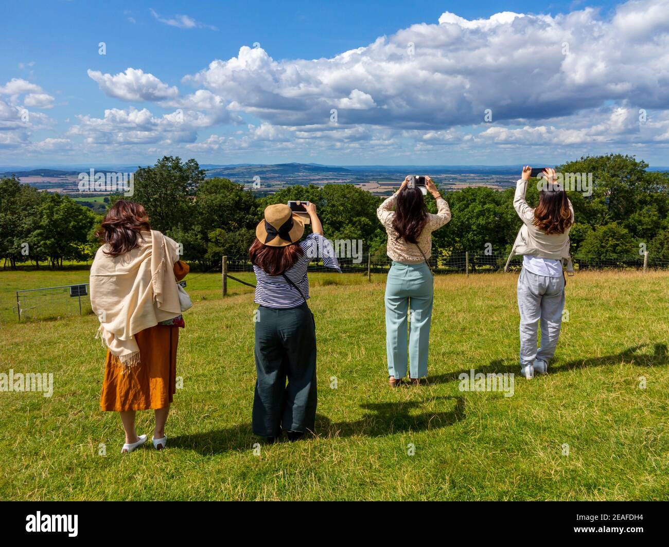 Group of four female tourists using mobile phones to photograph the