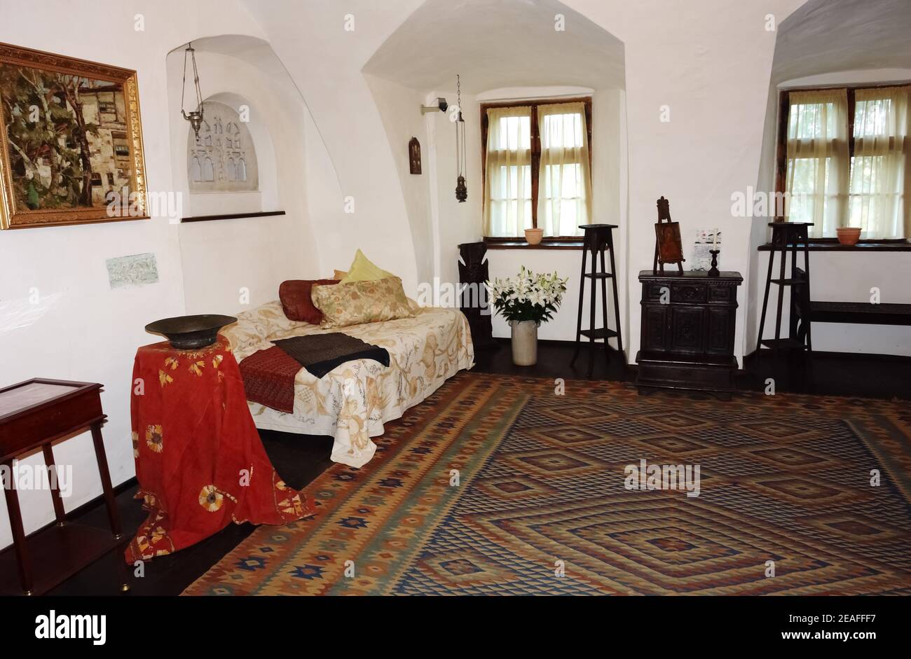 Interior of a room in an old castle with two windows, carved wooden furniture and a bed. Stock Photo