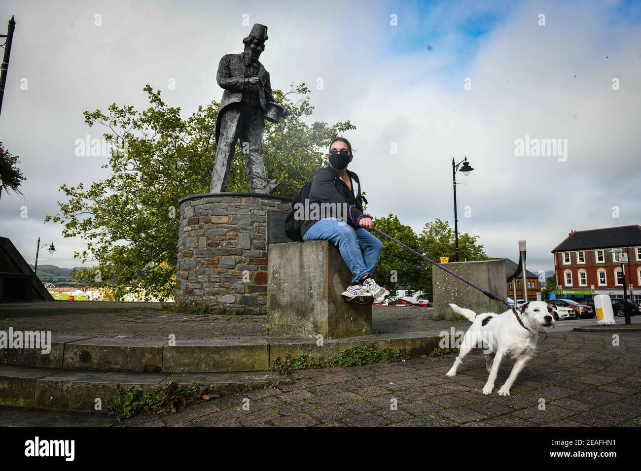 Caerphilly, Wales, UK. Resident, Claire Evans sits by the Tommy Cooper statue in the town of Caerphilly in south Wales, which has gone into lockdown along with it's wider borough area, after what is being described as a rapid increase in coronavirus cases. The Welsh government announced that from 6pm on Tuesday people will not be able to leave or enter the area without good reason, along with other restrictive measures. Stock Photo