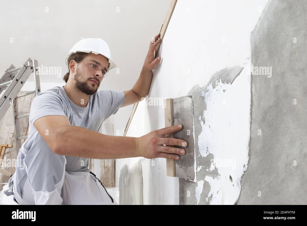 Hands man plasterer construction worker at work with trowel, plastering a wall, closeup Stock Photo
