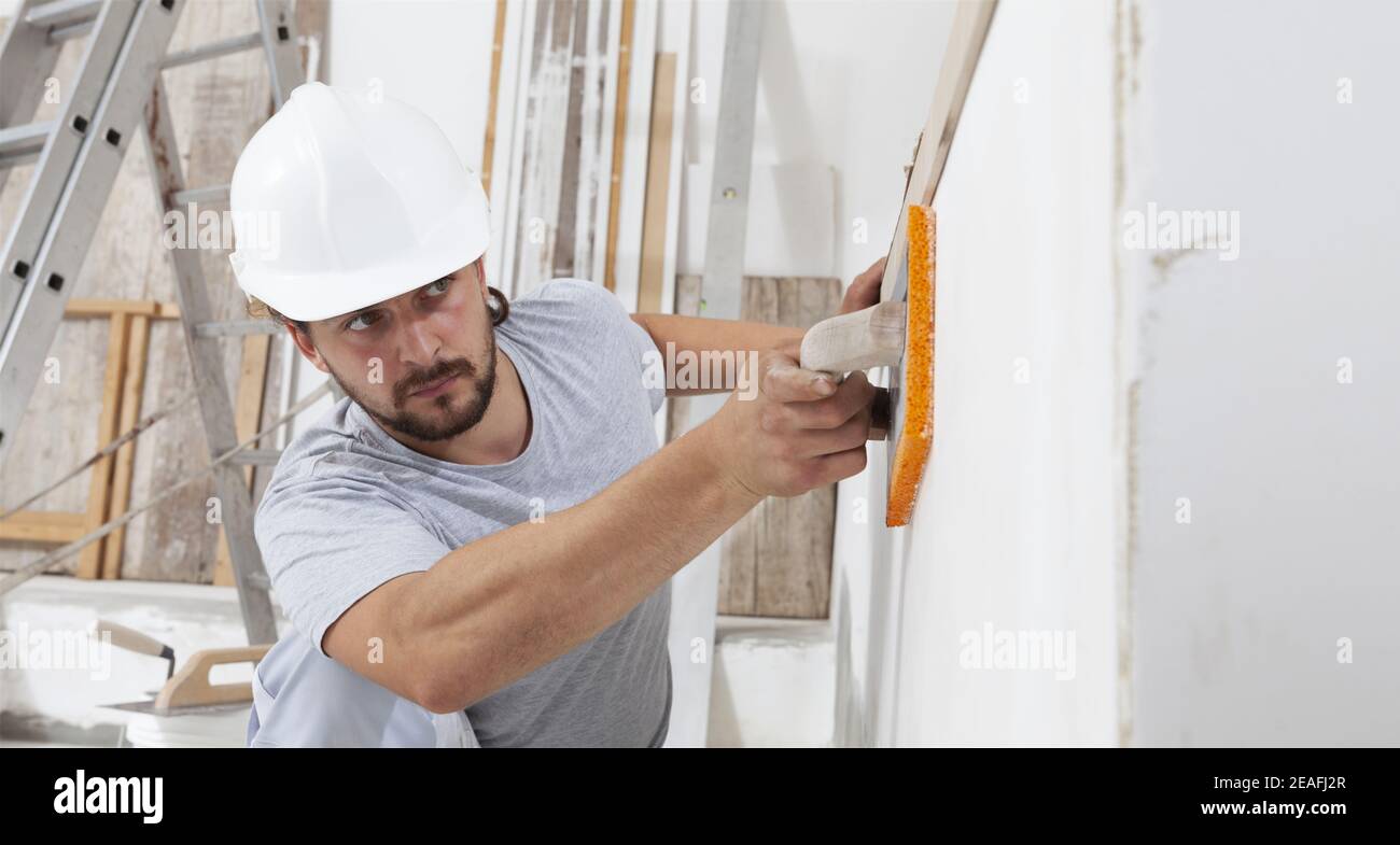 Construction worker are using sponge and plastering trowel to smooth the walls. Home improvement, hands plasterer man at work in interior construction Stock Photo