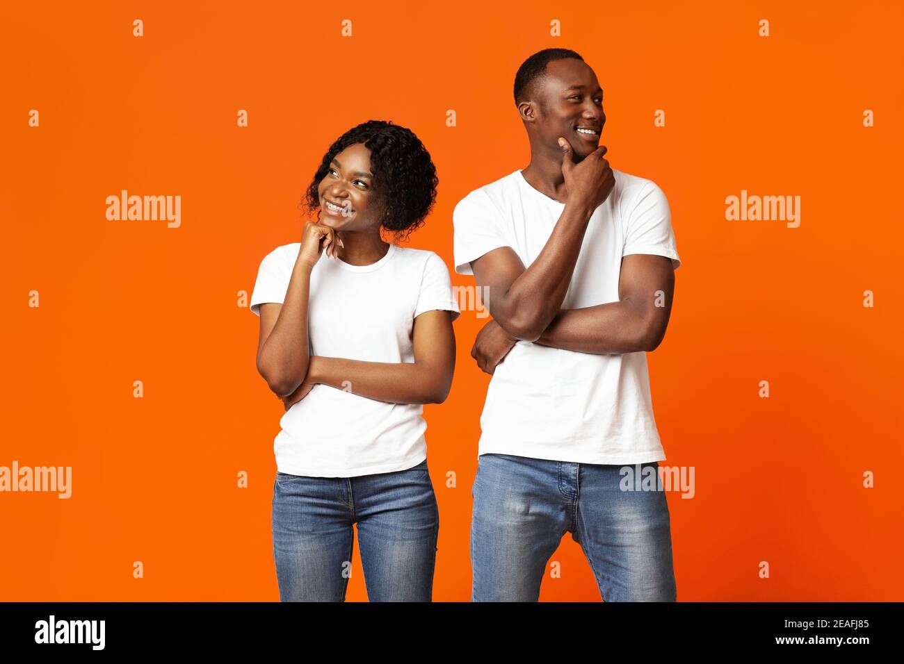 Young black couple day dreaming on orange background Stock Photo