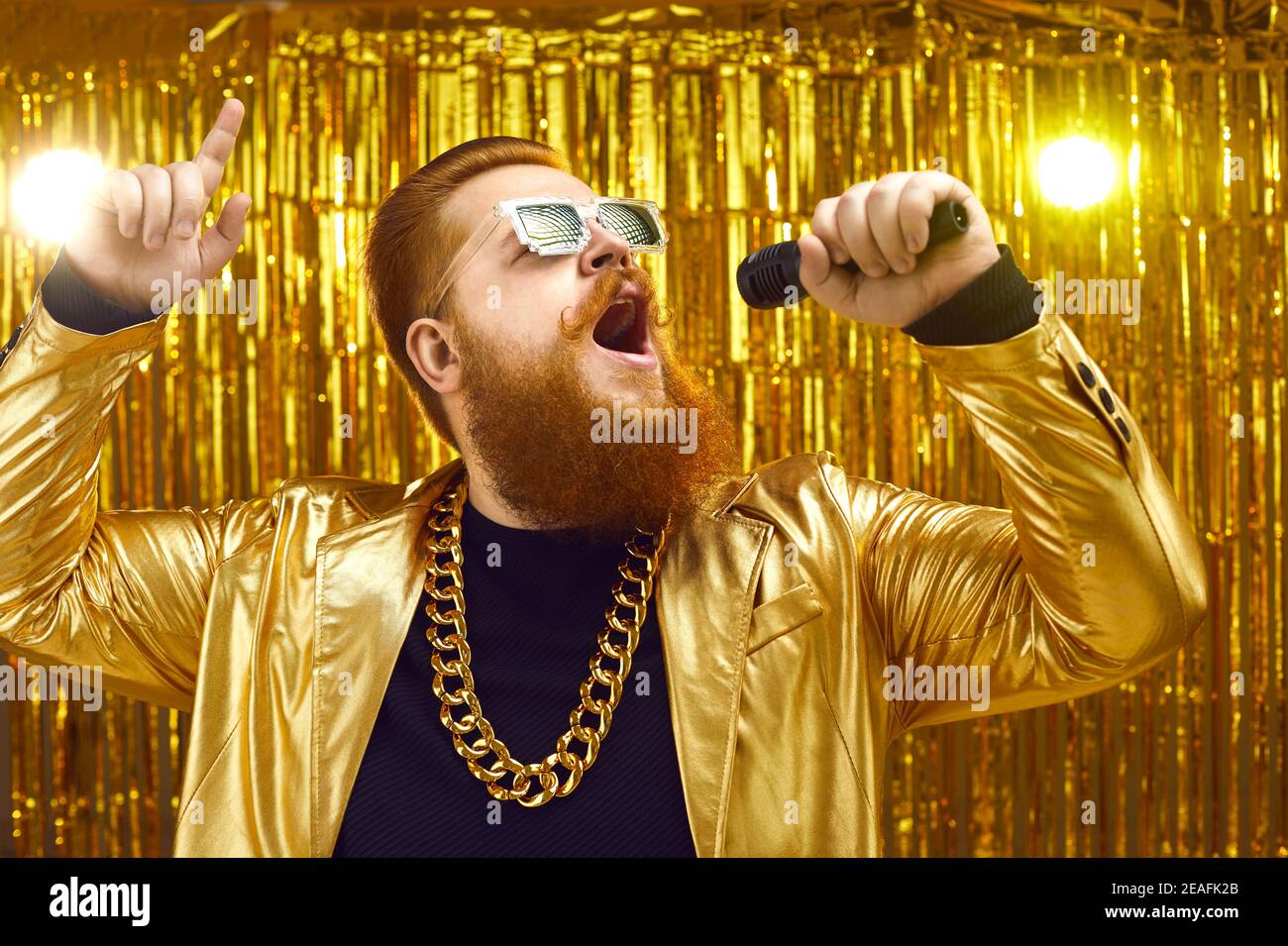 Singer in extravagant shiny jacket holding microphone and singing songs at concert Stock Photo