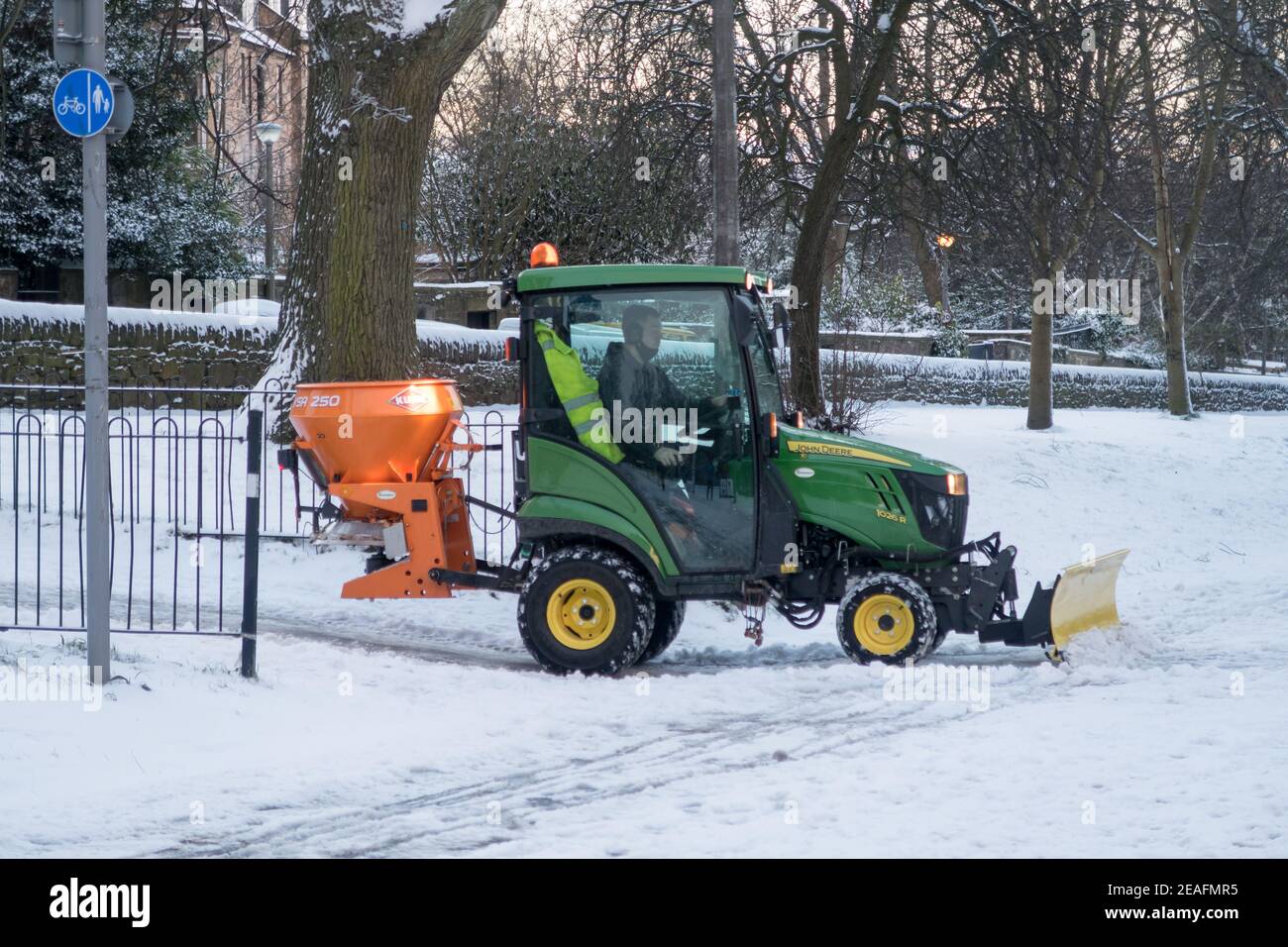 A man driving a tractor spreading salt along the Meadows park in Edinburgh city center. Stock Photo