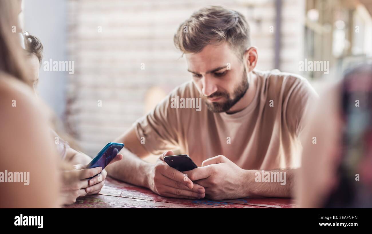 Alienation addiction. Group of friend sitting in cafe and typing on ...